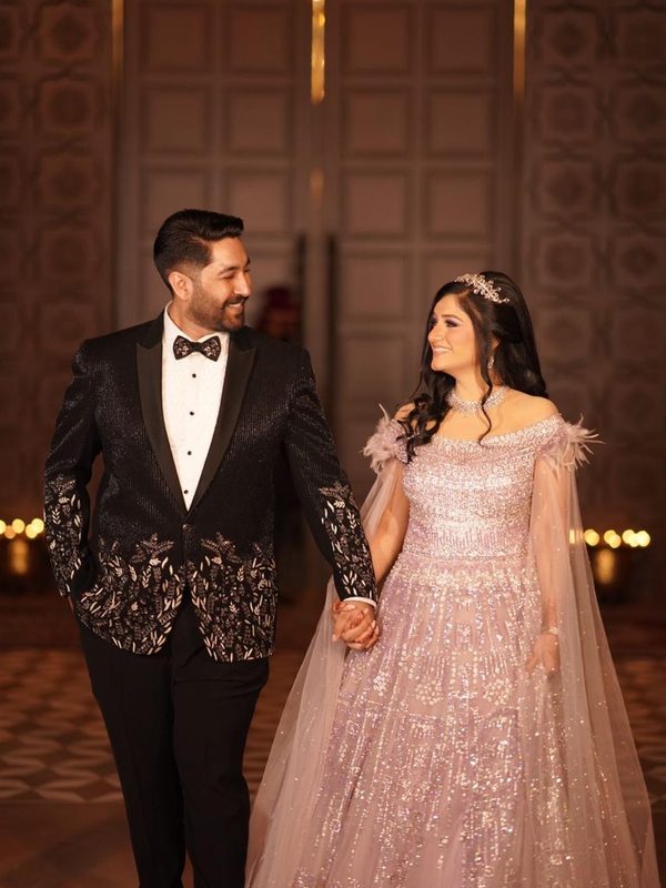 The couple walking hand in hand, smiling at each other.