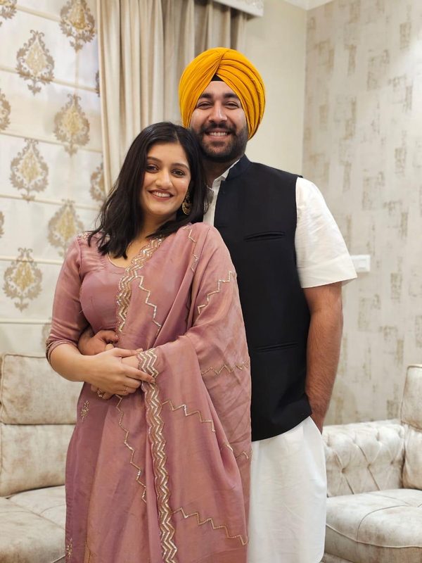 The couple smiling at home in festive clothes.