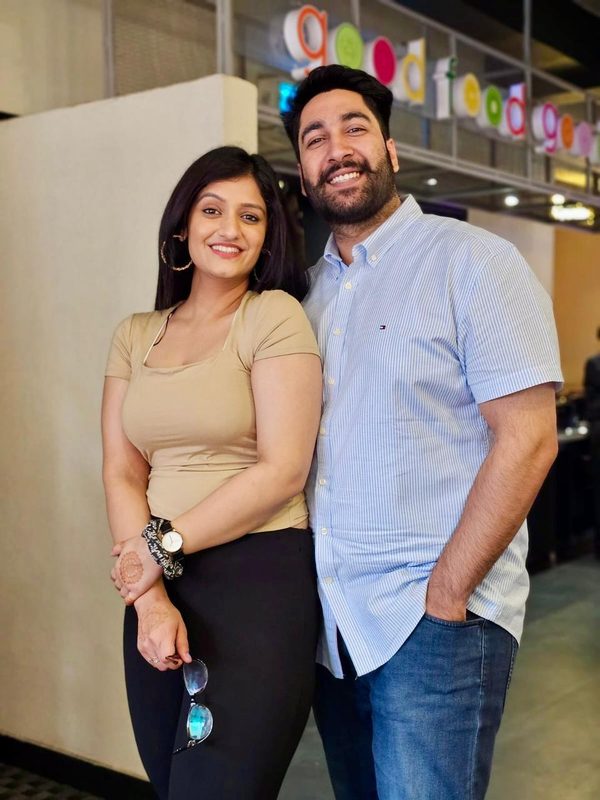 The couple smiling side by side on a day out.
