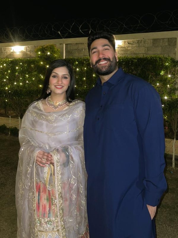 The couple in a garden at night under fairy lights.